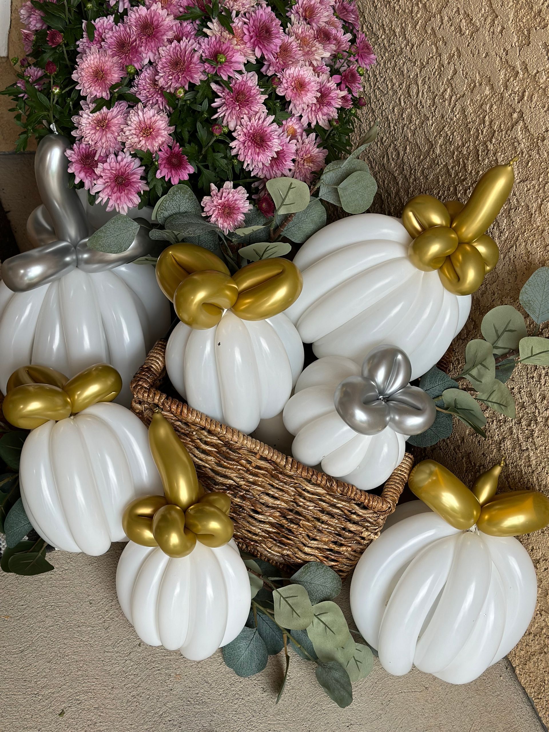 White balloon pumpkins with gold and silver stems, arranged with flowers in a basket.