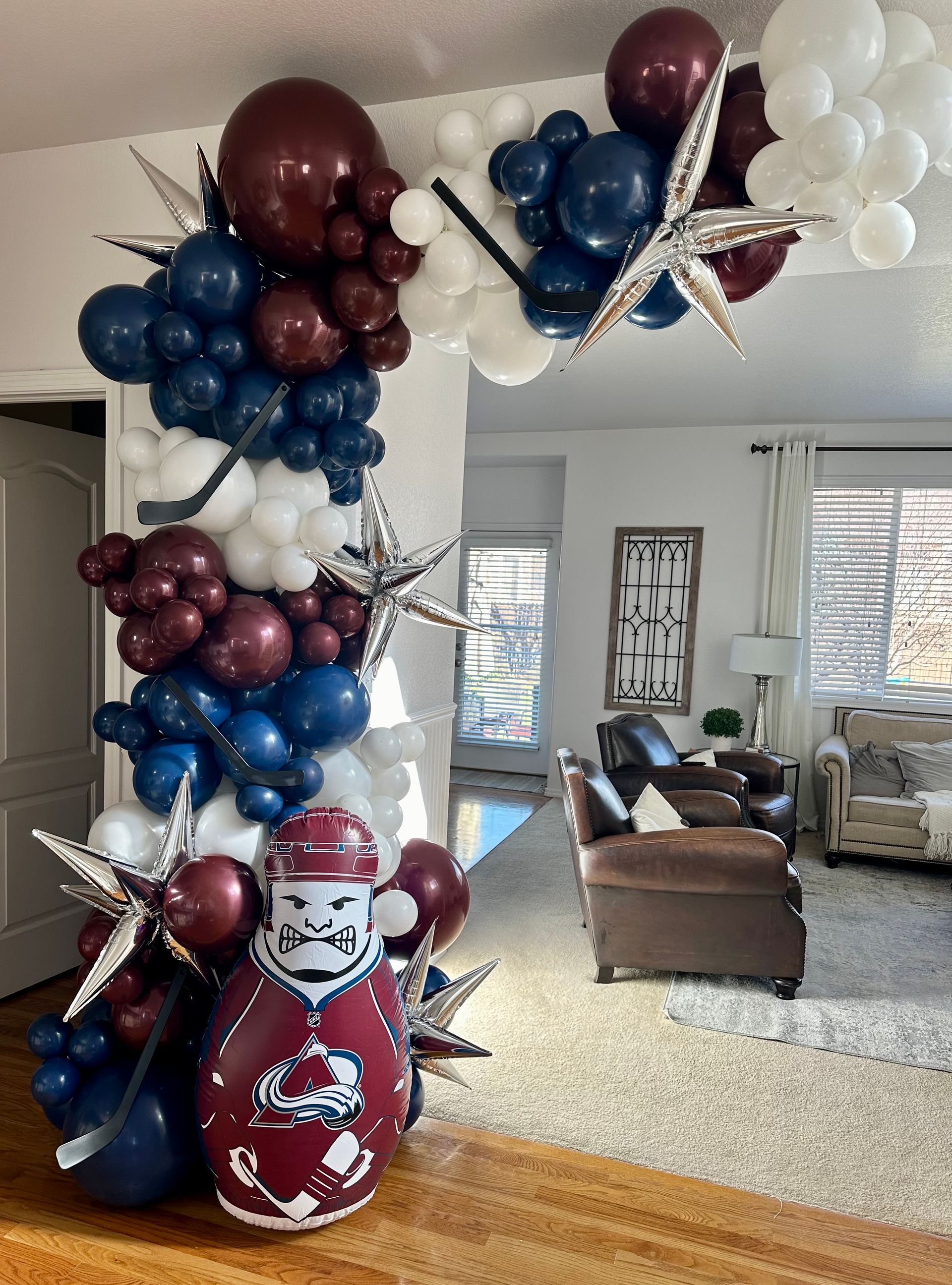 Balloon arch with white, navy, and burgundy balloons; silver stars; Santa figure.