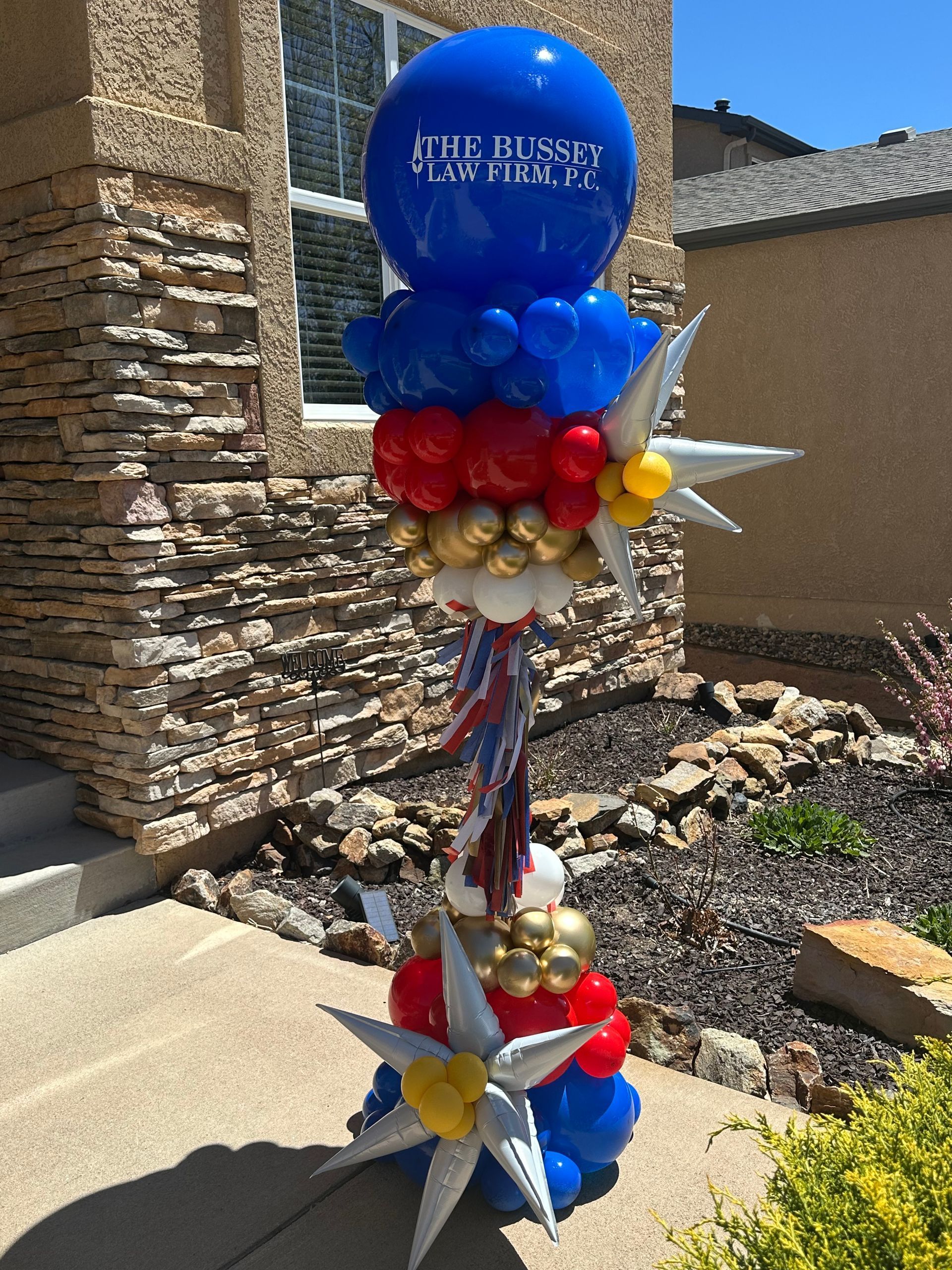 A balloon sculpture in red, white, blue, and gold, with a large blue top balloon.
