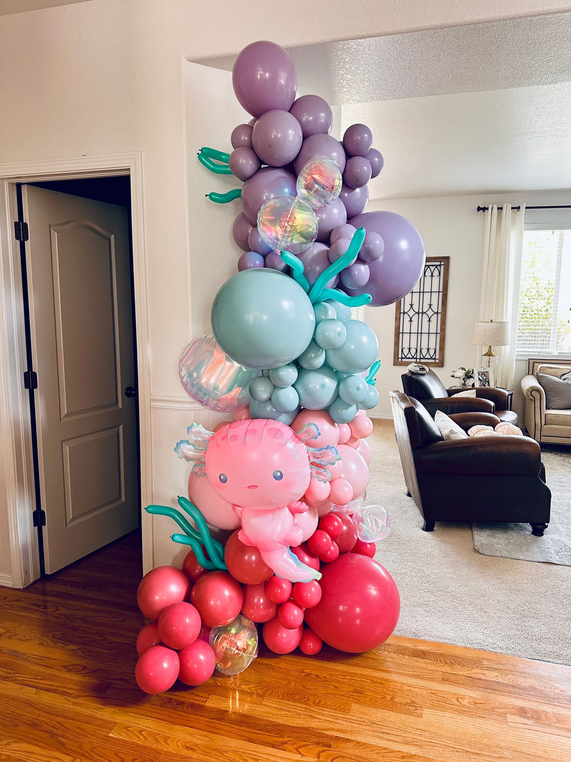 Mermaid-themed balloon arch in various shades of pink, purple, and blue, decorating a doorway.