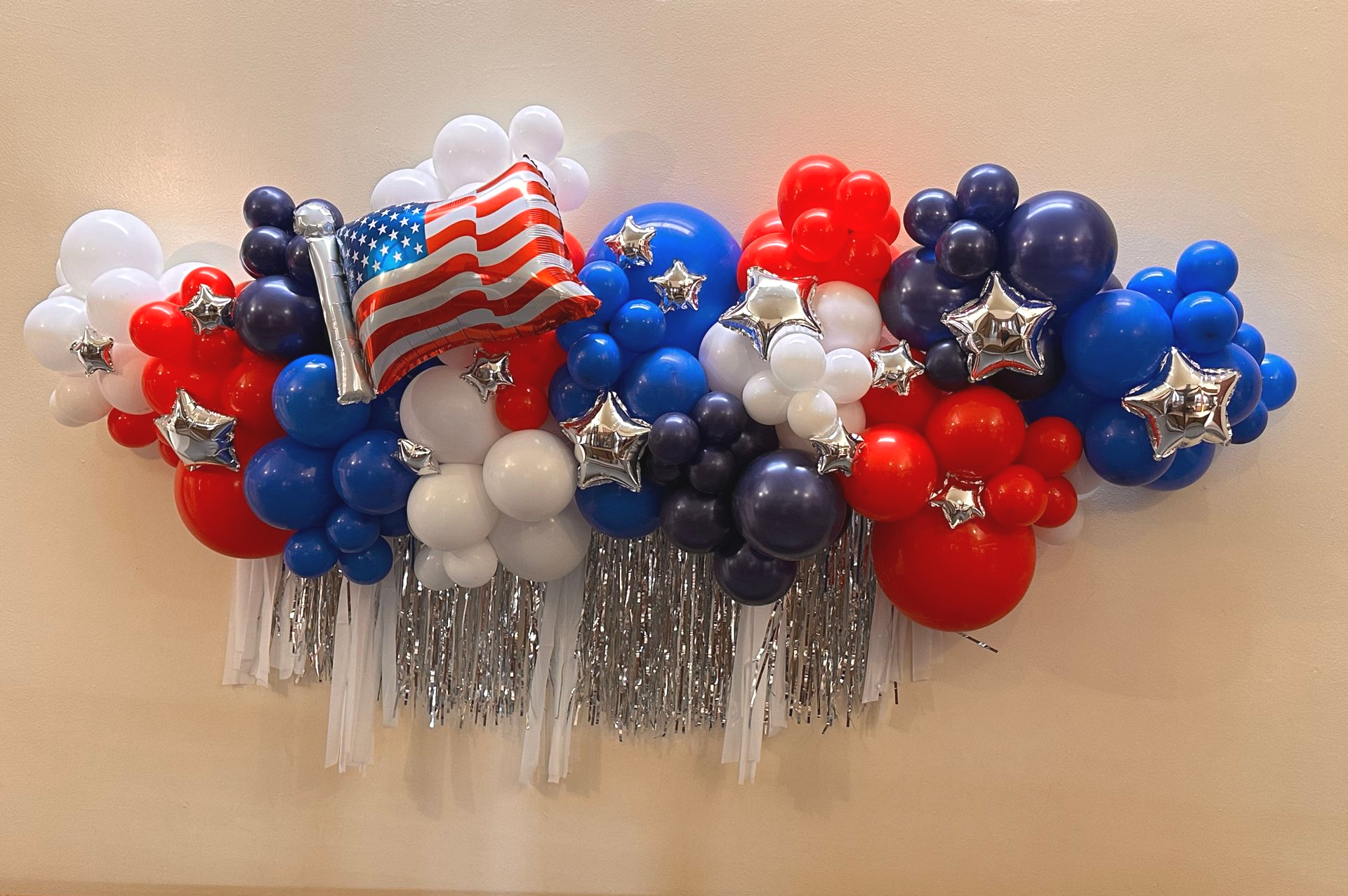 Patriotic balloon garland: red, white, and blue balloons, silver fringe, and American flag.