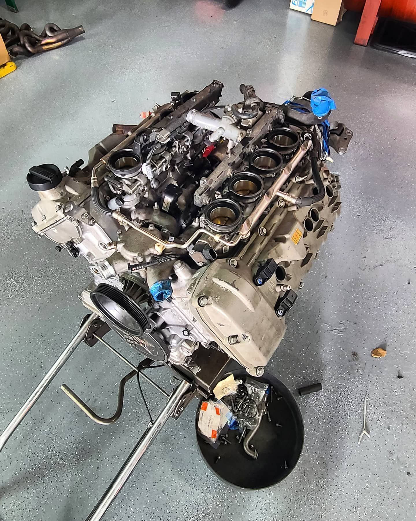 V8 engine on a stand; grey, silver, and black components; in a garage setting.