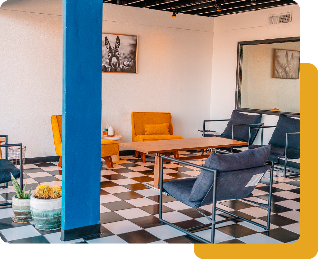 Modern lounge with checkerboard floor, blue pillar, yellow chair, gray sofas, and low wooden table.