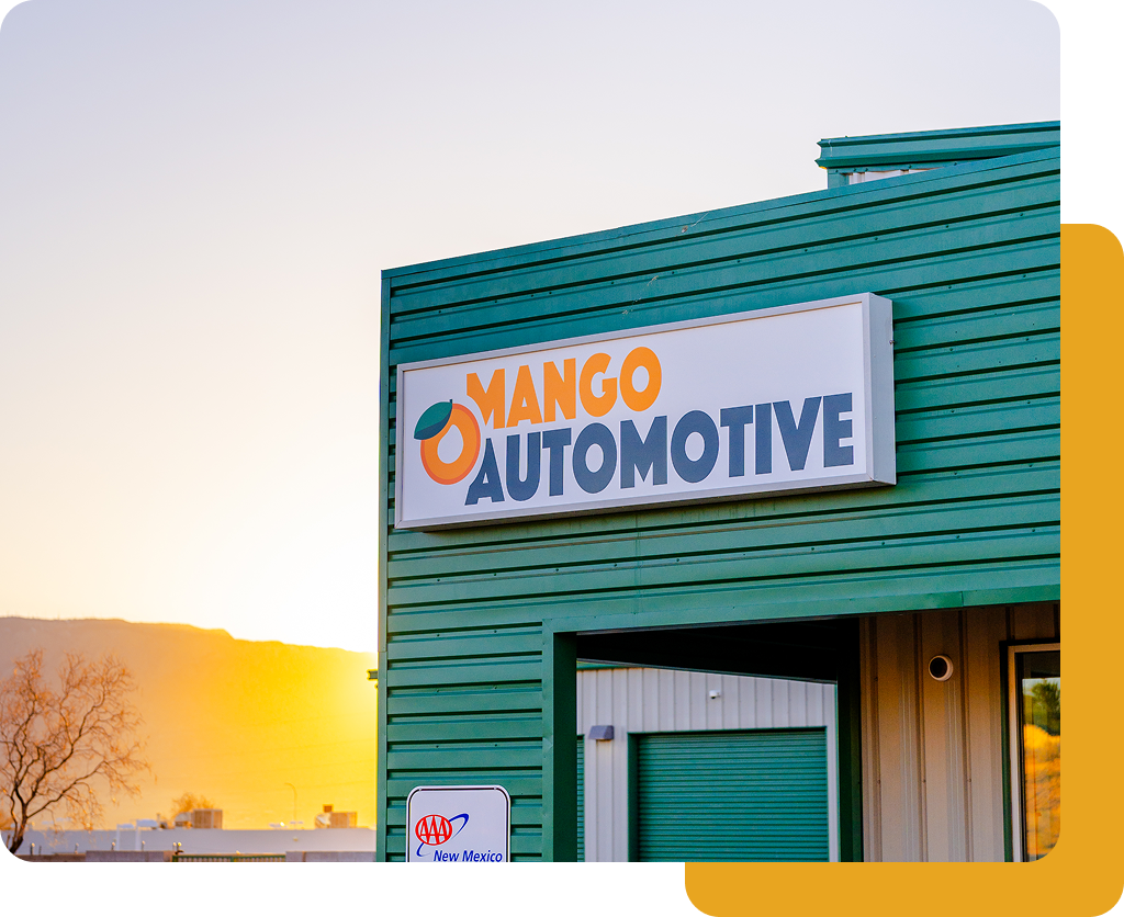 Mango Automotive storefront sign on a teal building at sunset