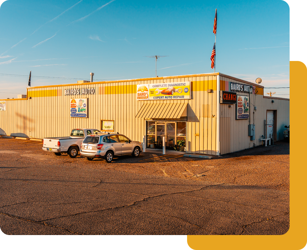 Small tan commercial building with parked cars under a clear blue sky at sunset