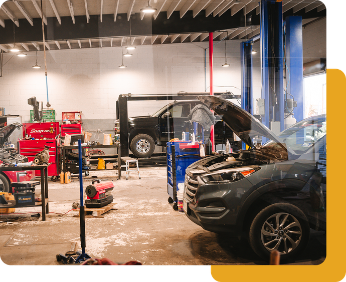 Auto repair shop with two cars on lifts, tools, and a mechanic bay floor