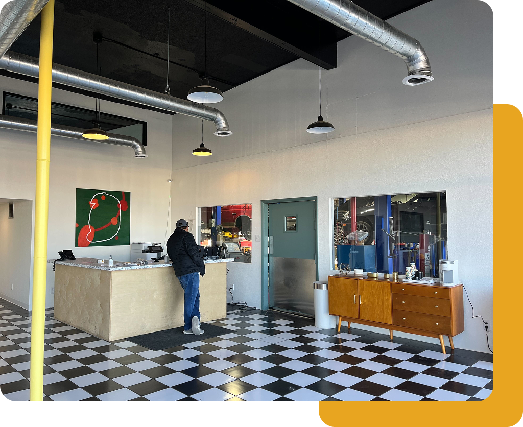 Modern cafe with black-and-white checkered floor, counter, and a person standing near the register