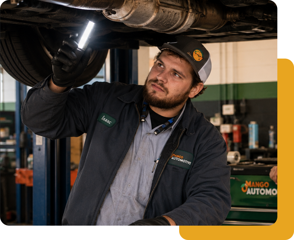 Mechanic inspecting undercarriage of a vehicle with a flashlight in an auto shop