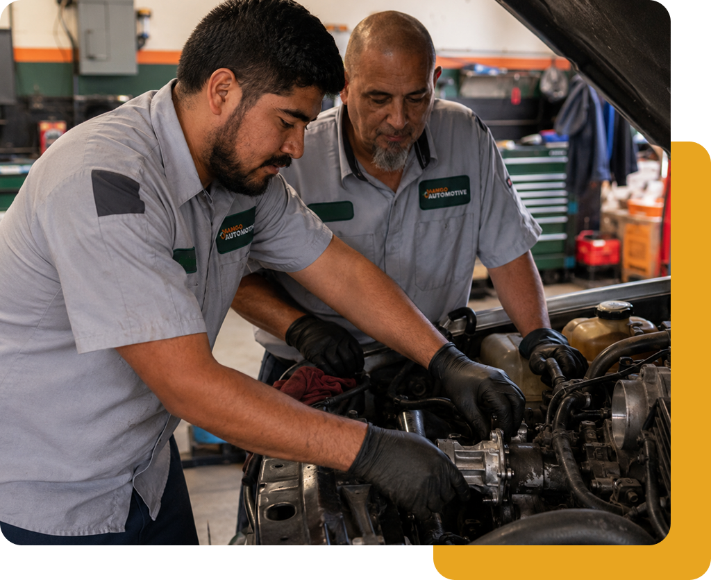Two Mango Automotive technicians repairing an engine