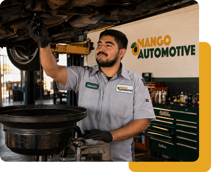 Mechanic working under a car lift in a Mango Automotive shop, with tool cabinets in the background