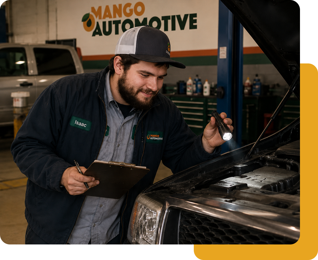 Mechanic in a garage inspects a car engine with clipboard while wearing a cap and jacket