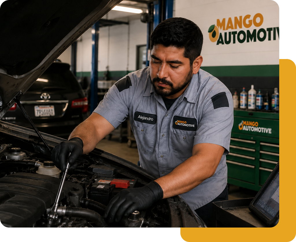 Mechanic in gray uniform working on a car engine in an auto repair shop