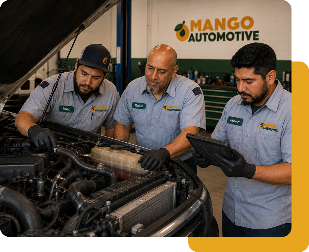 Three mechanics in gray uniforms inspecting a car engine under the hood at Mango Automotive.