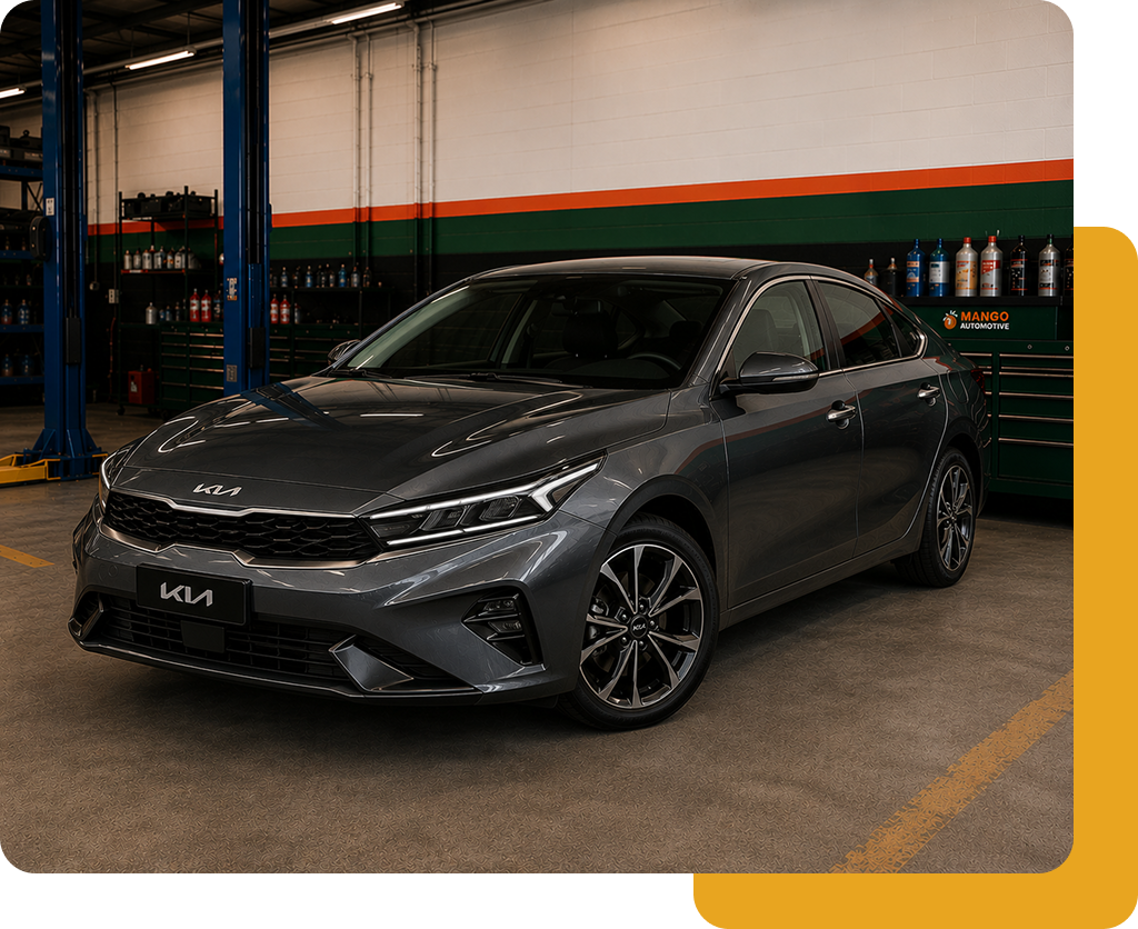 Gray Kia sedan in a garage, angled front view with black wheels and headlights on display