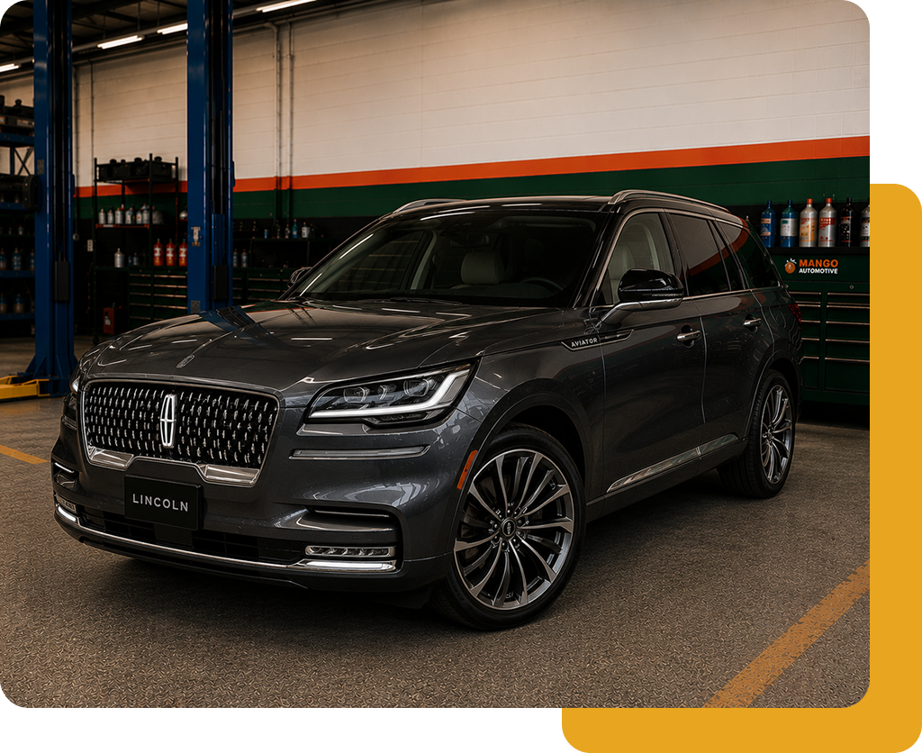 Dark gray Lincoln SUV parked indoors near service bays, with chrome grille and alloy wheels.