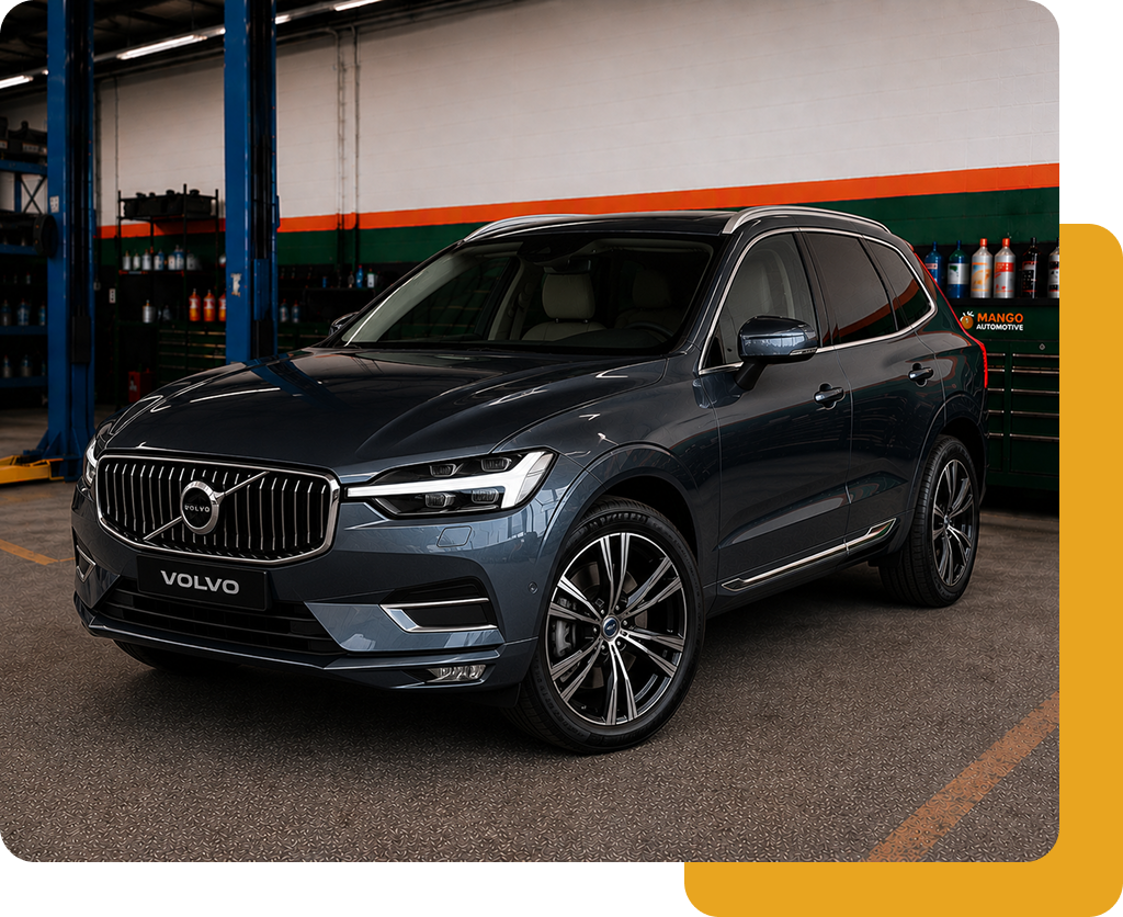 Gray Volvo SUV parked indoors, front view, with sleek headlights and black grille.