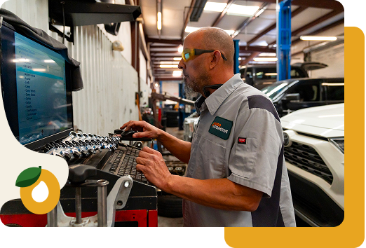 Mechanic working on a car engine at a computer-controlled diagnostic station in a workshop