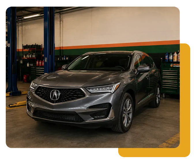 Gray Acura SUV parked in an auto shop garage with blue lifts and yellow-striped wall