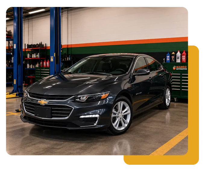 Black Chevrolet sedan in a garage, parked by tool cabinets and a car lift.