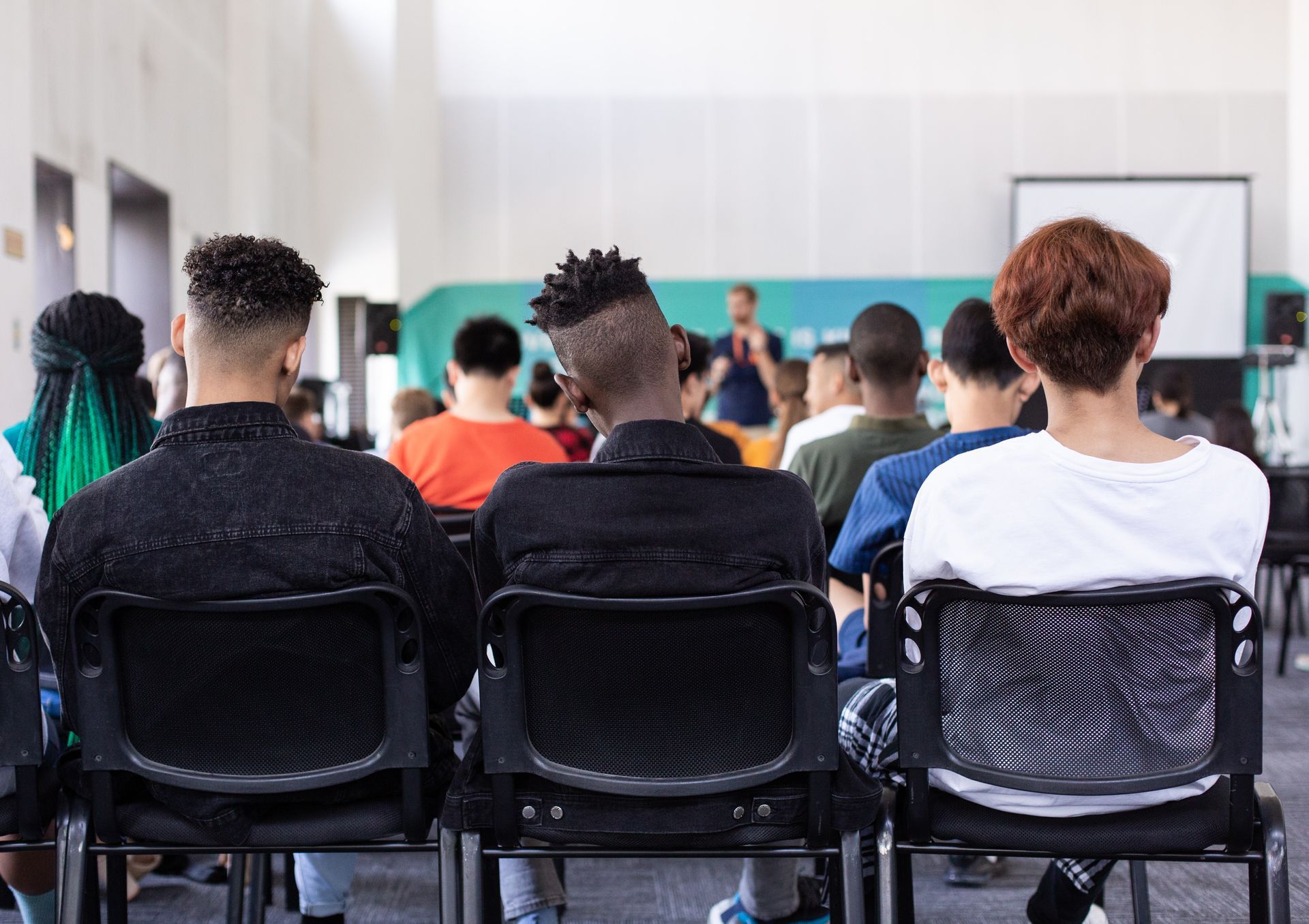 Students seated, facing presenter in a brightly lit lecture hall.