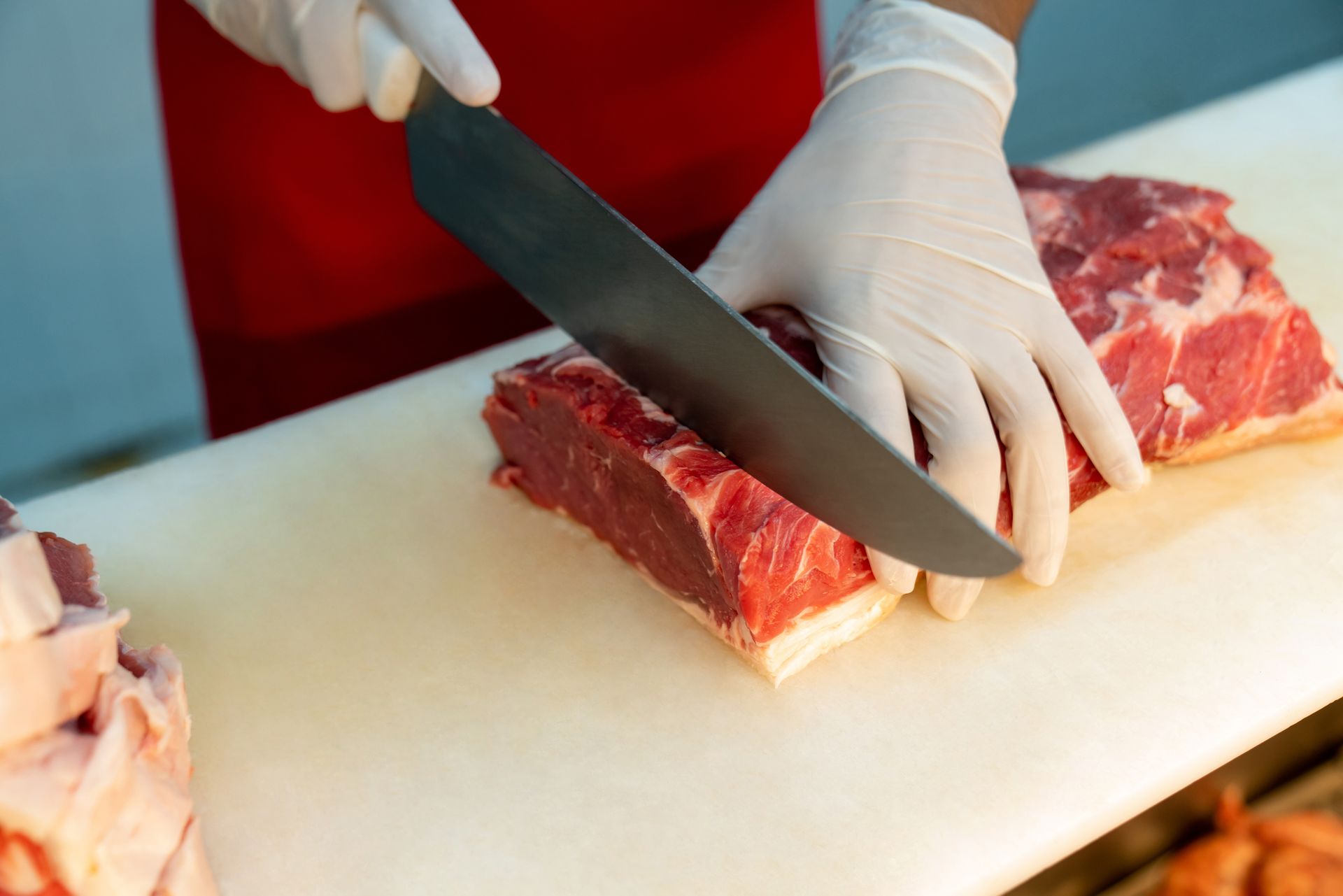 A person is cutting a piece of meat on a cutting board.