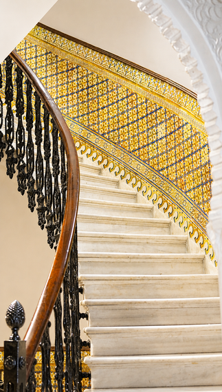 Elegant curved staircase with cream steps, black railing, and gold decorative banister detail