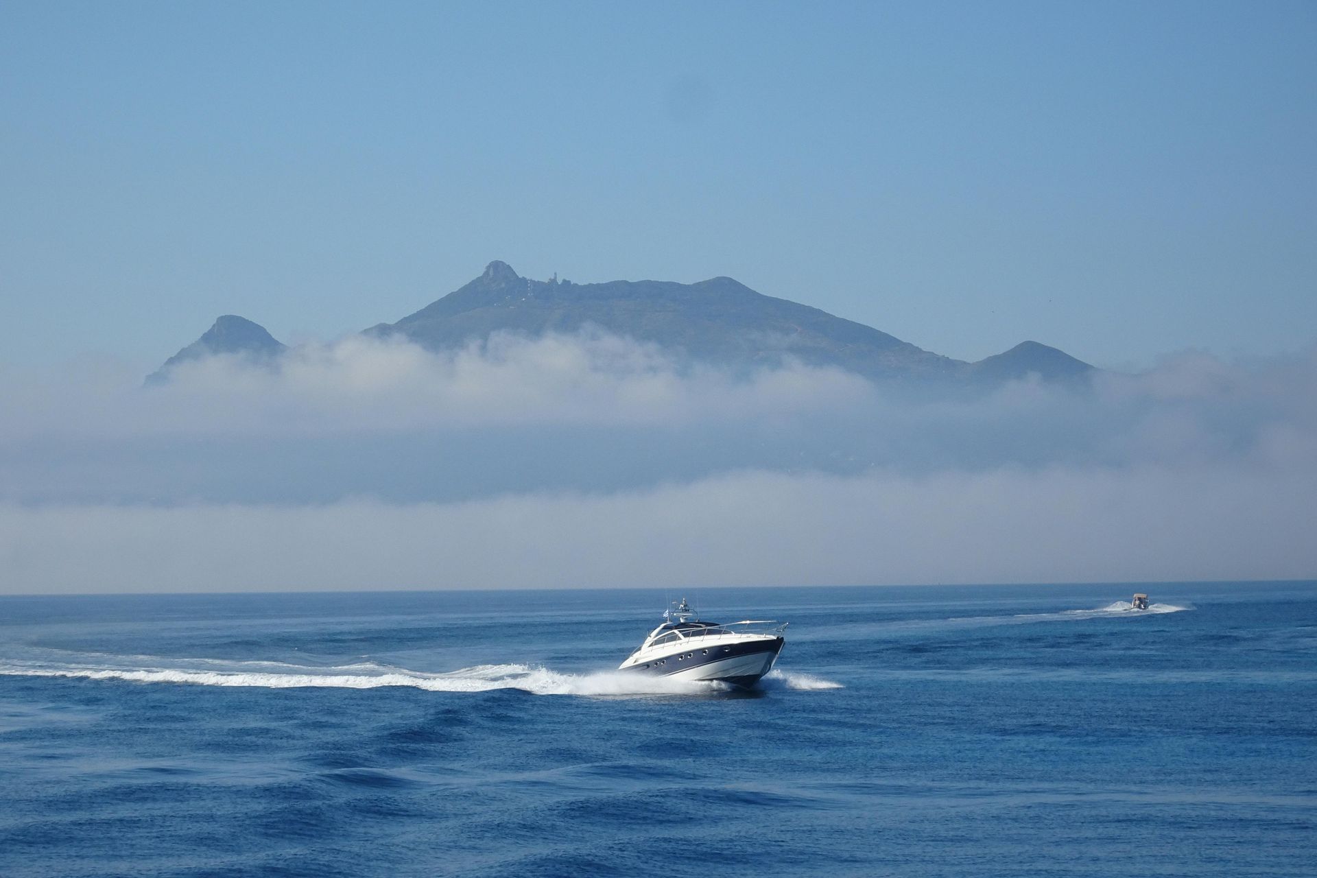 Motorboat speeding across blue water with a misty island in the background