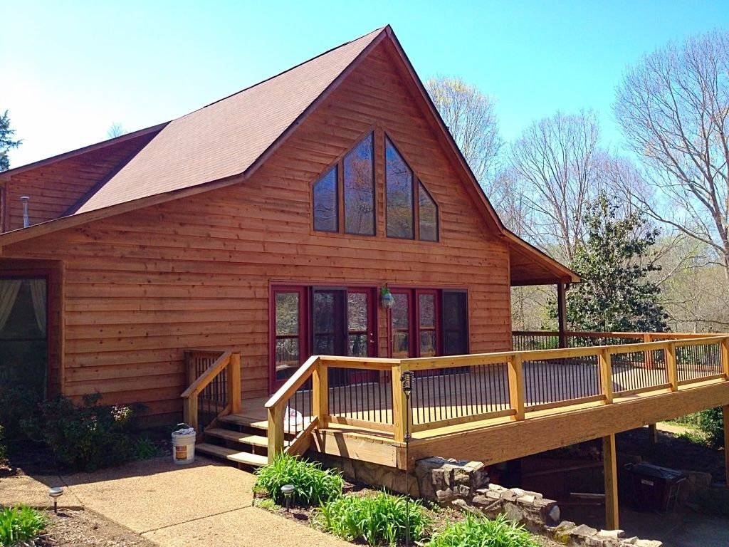 A large log cabin with a large deck and stairs