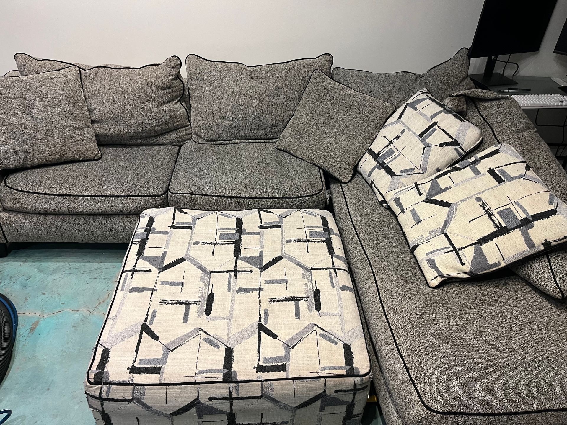 Gray sectional sofa with patterned ottoman and pillows in a living room