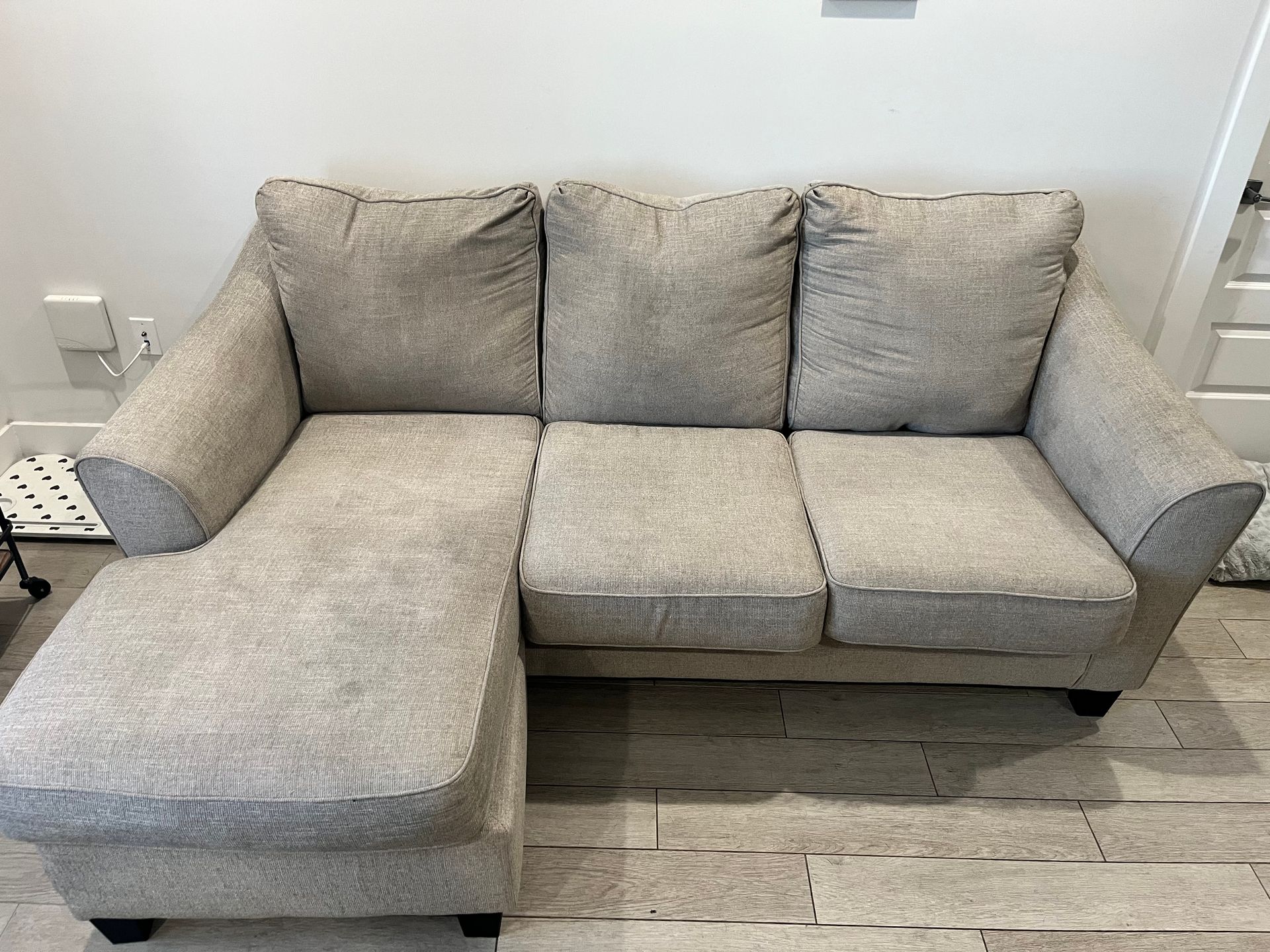 Gray sectional sofa with chaise in a light-colored room on tiled flooring