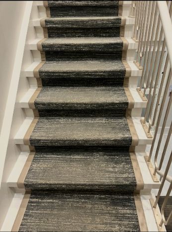 Carpeted staircase with dark runner and white banister railing indoors