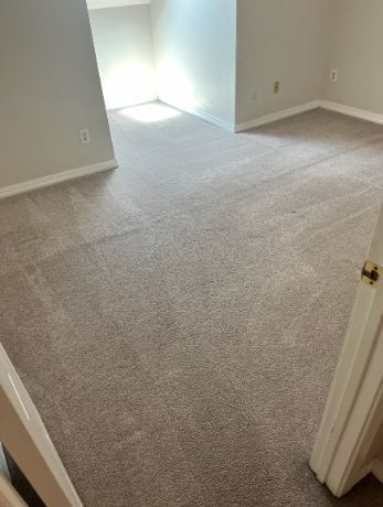 Empty carpeted room with white walls and a bright window nook.