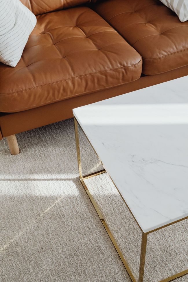 Modern living room with a brown sofa and white marble coffee table on a light carpet