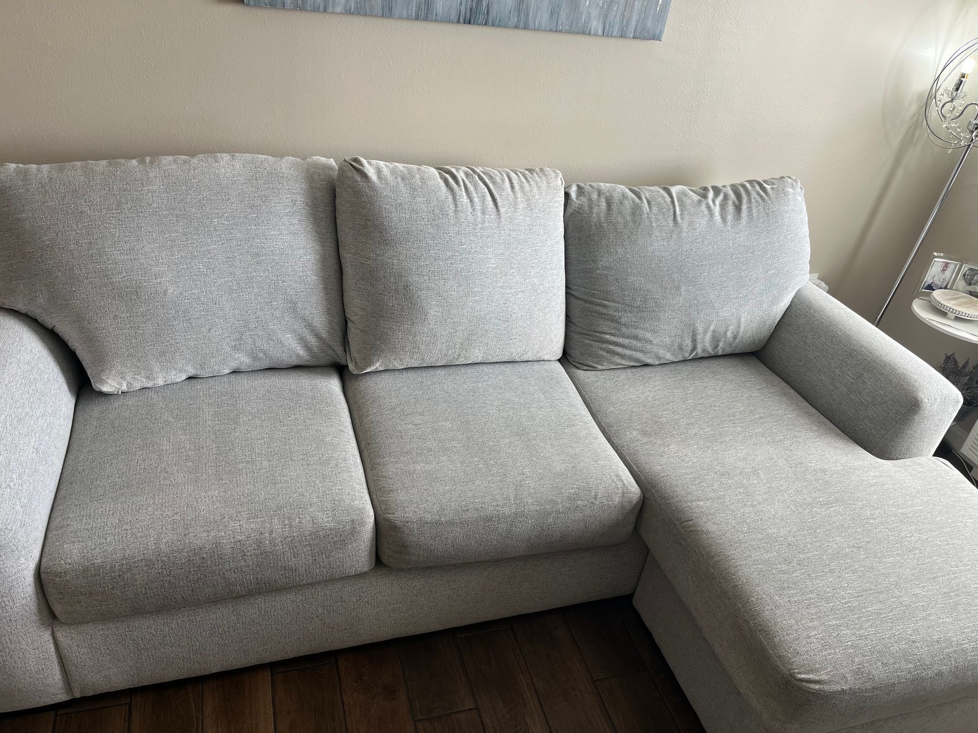 Gray L-shaped sectional sofa with three back cushions and chaise lounge in a living room