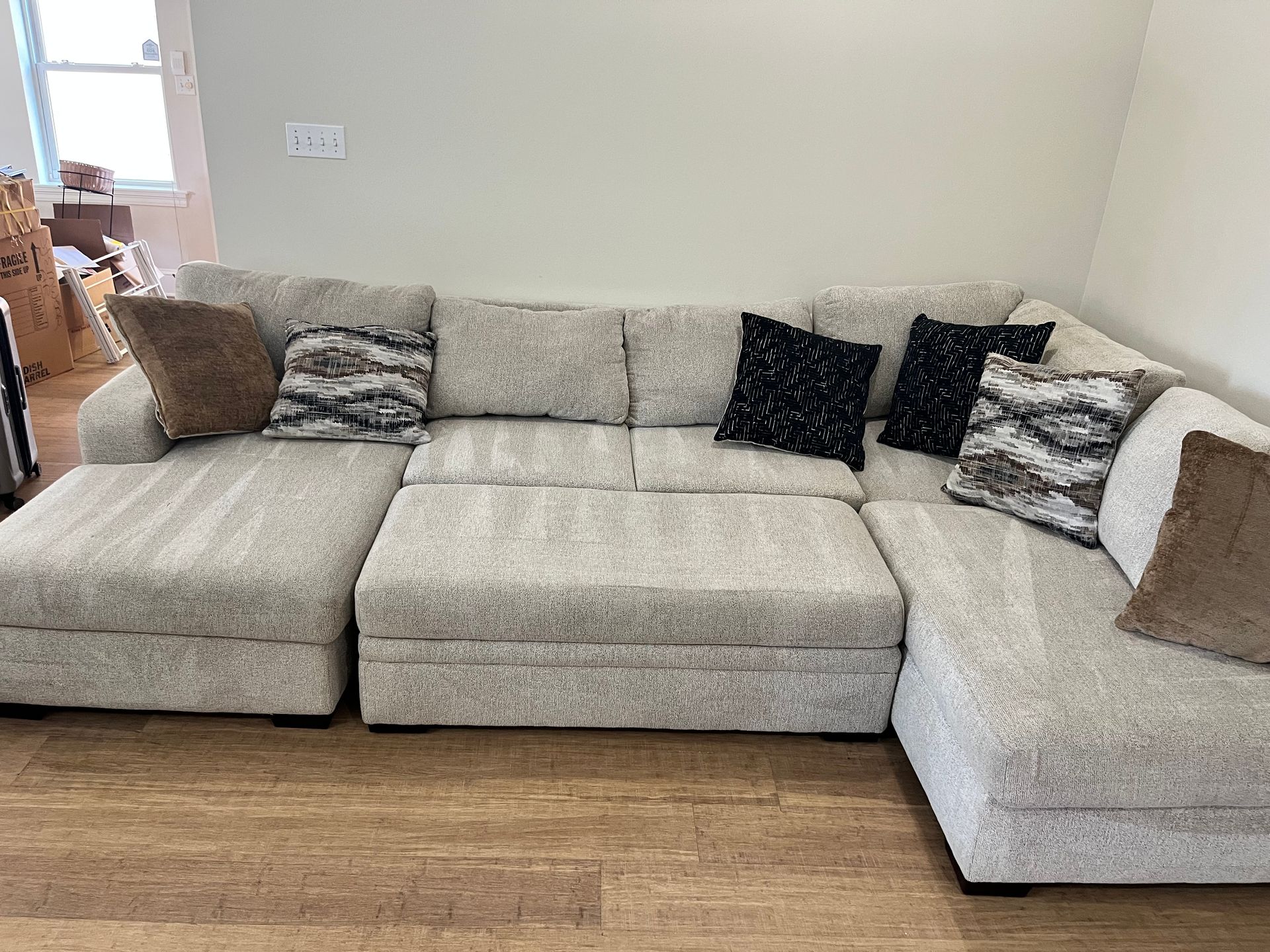 L-shaped beige sectional sofa with patterned pillows in a bright living room.