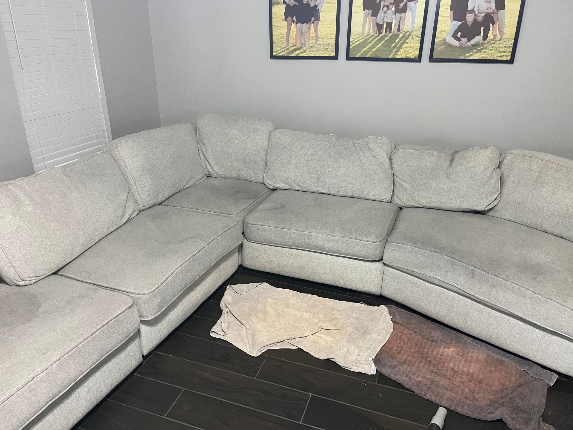Light gray sectional sofa in a living room with a blanket on the dark wood floor