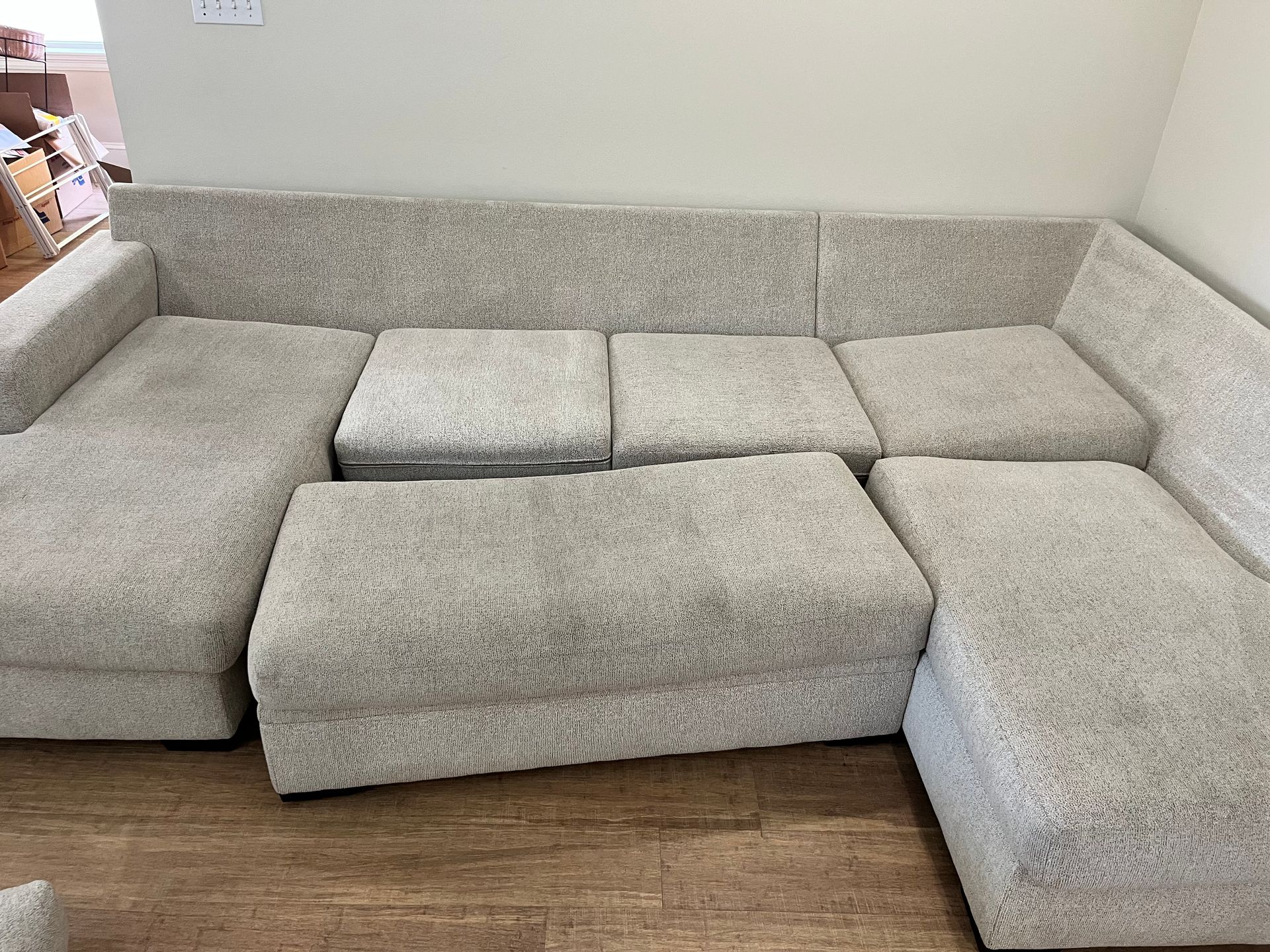 Gray sectional sofa with loose cushions in a living room corner on a wood floor