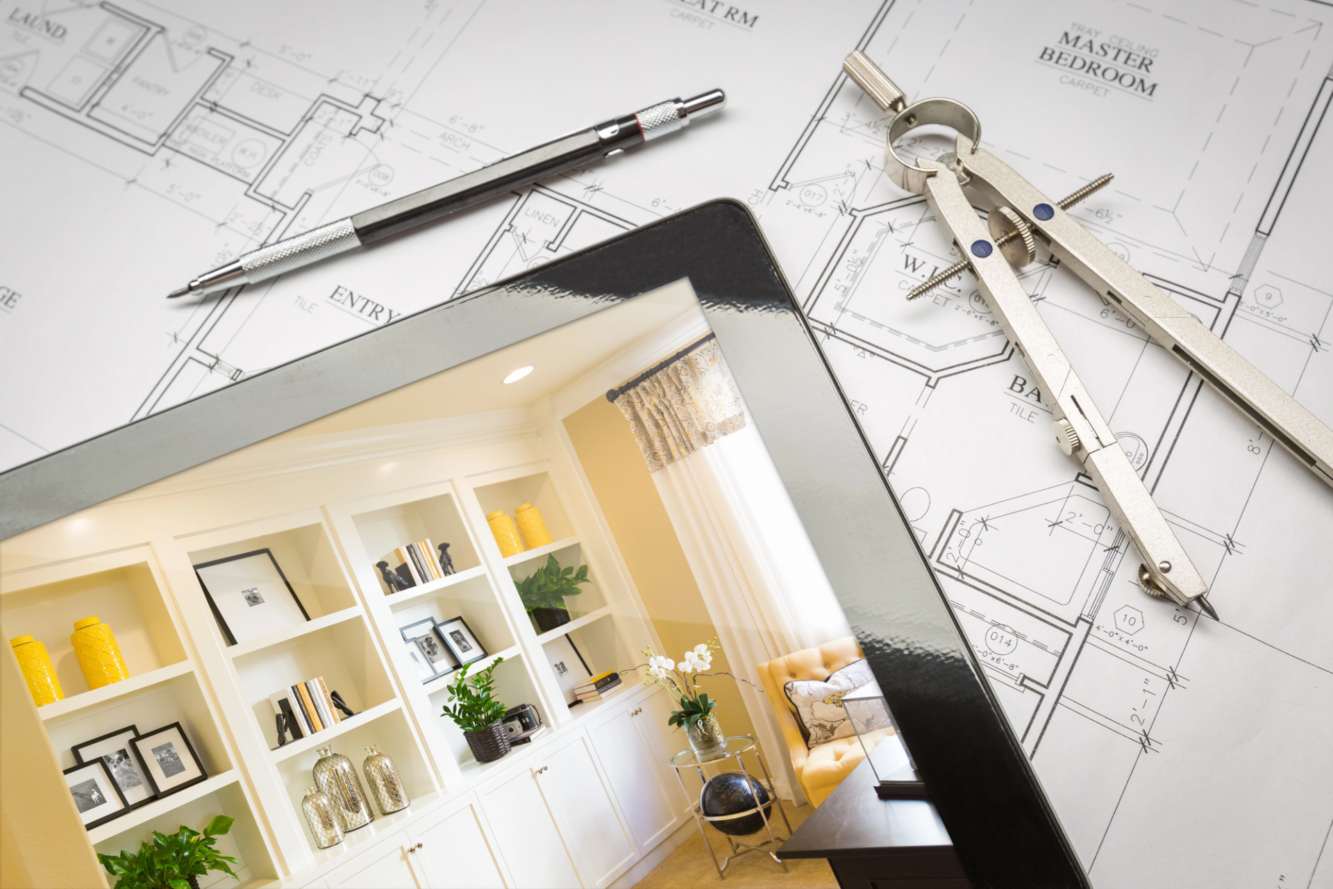 A tablet displaying an elegant living room interior is placed on architectural blueprints. Nearby are a mechanical pencil and a pair of compasses, conveying a design theme.