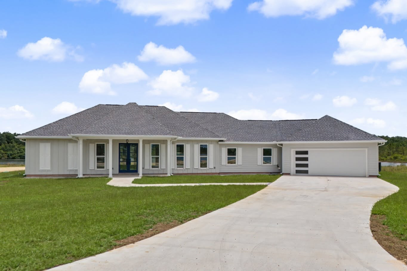 Front exterior of a completed single-story custom home with a curved driveway and attached garage