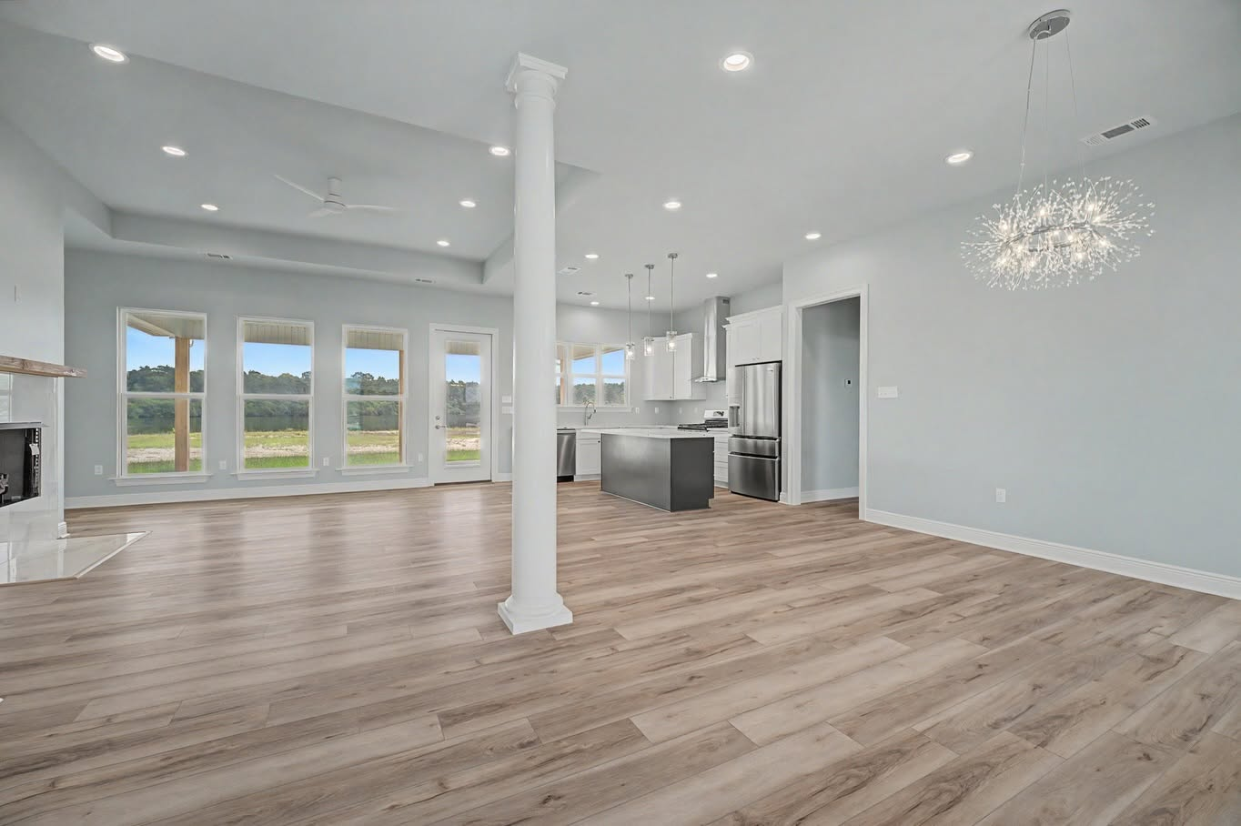 Spacious open-concept living area with a custom kitchen, fireplace and statement chandelier