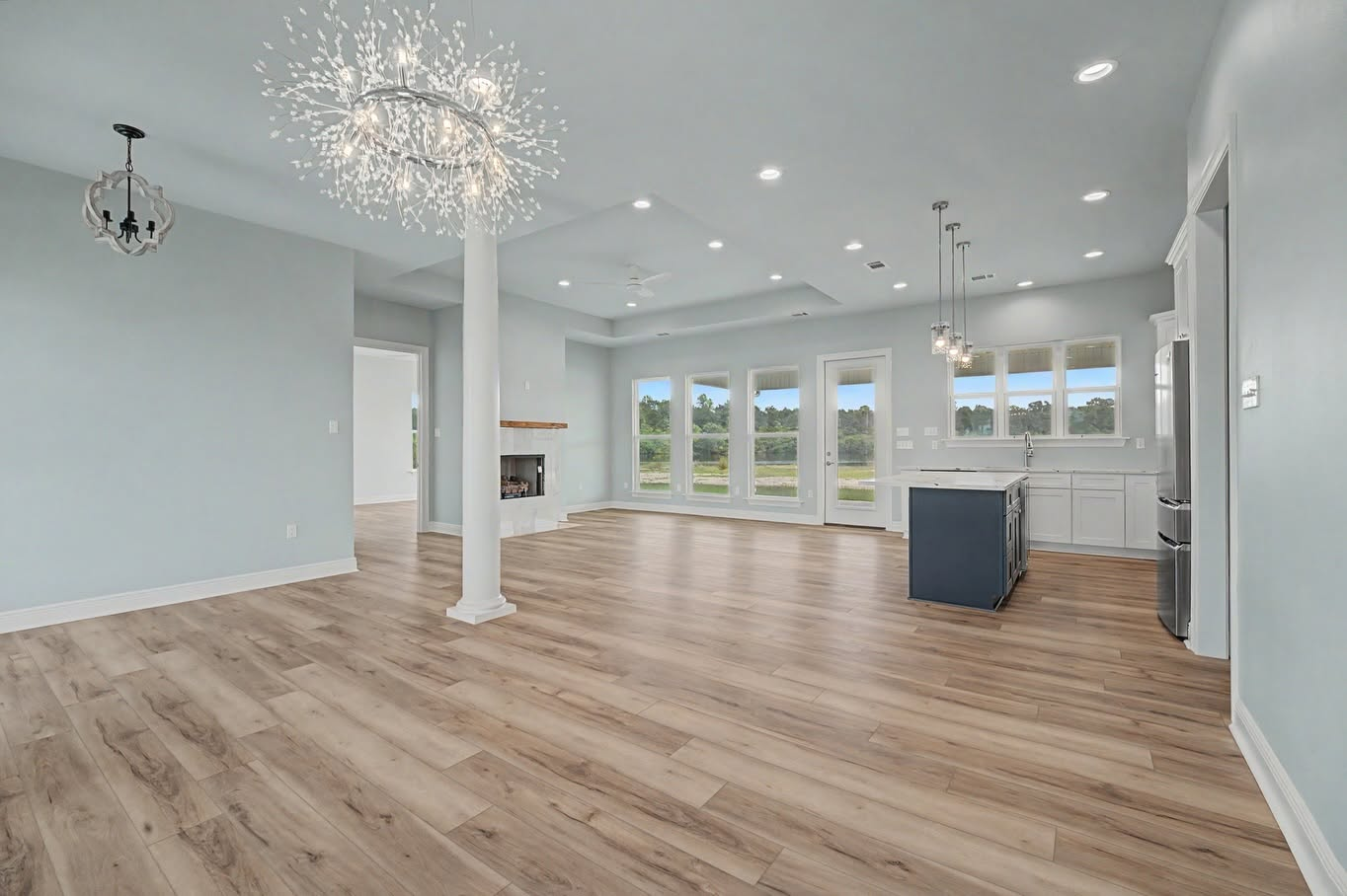 Open living and kitchen area in a Louisiana custom home with large windows and modern lighting