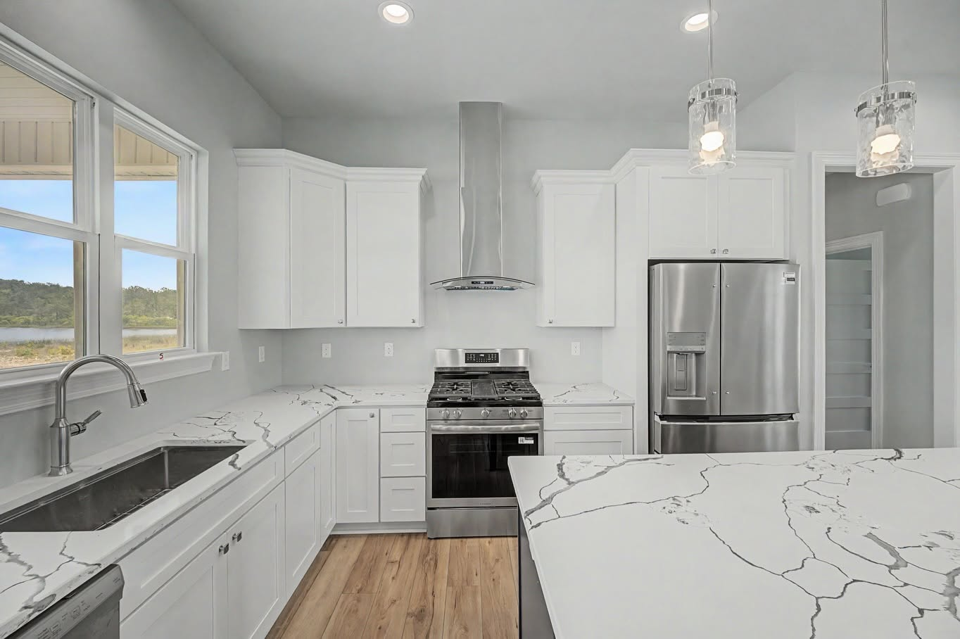White custom kitchen with quartz countertops, stainless steel appliances and a large island