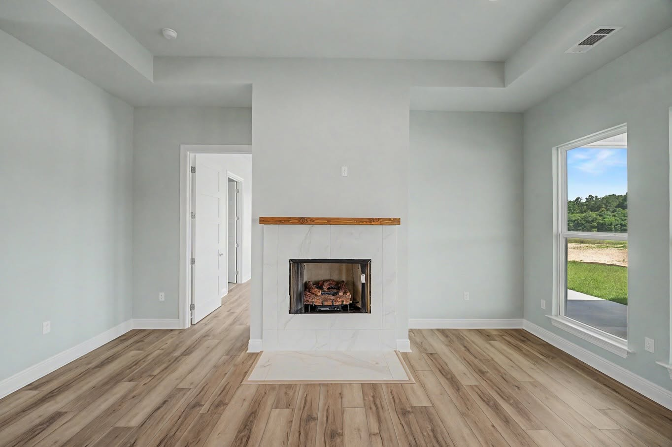 Custom living room fireplace with a wood mantel and large windows