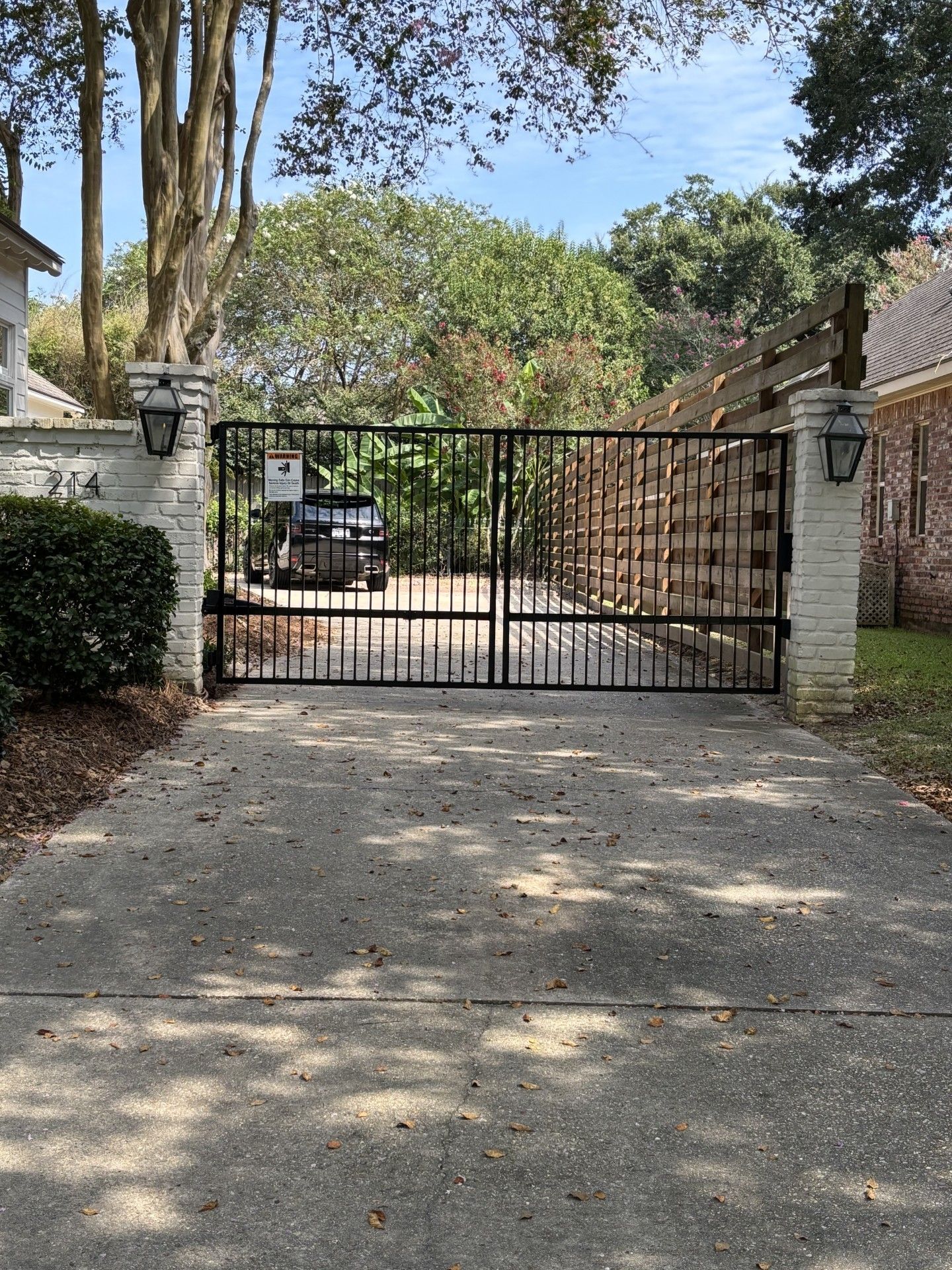 Black wrought iron gate with arched top and stone pillars at a home's entrance.