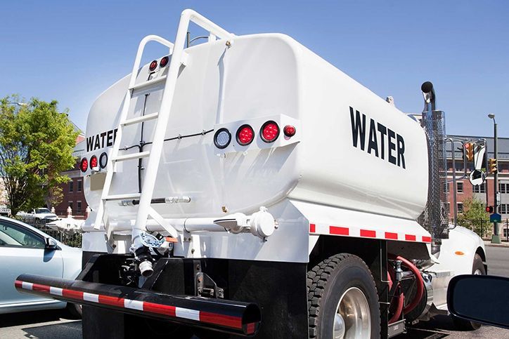 Rear and side view of parked water tanker truck.