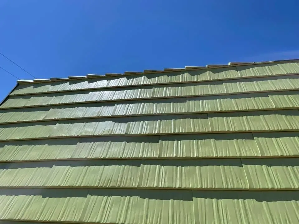 Green corrugated roof against a clear blue sky
