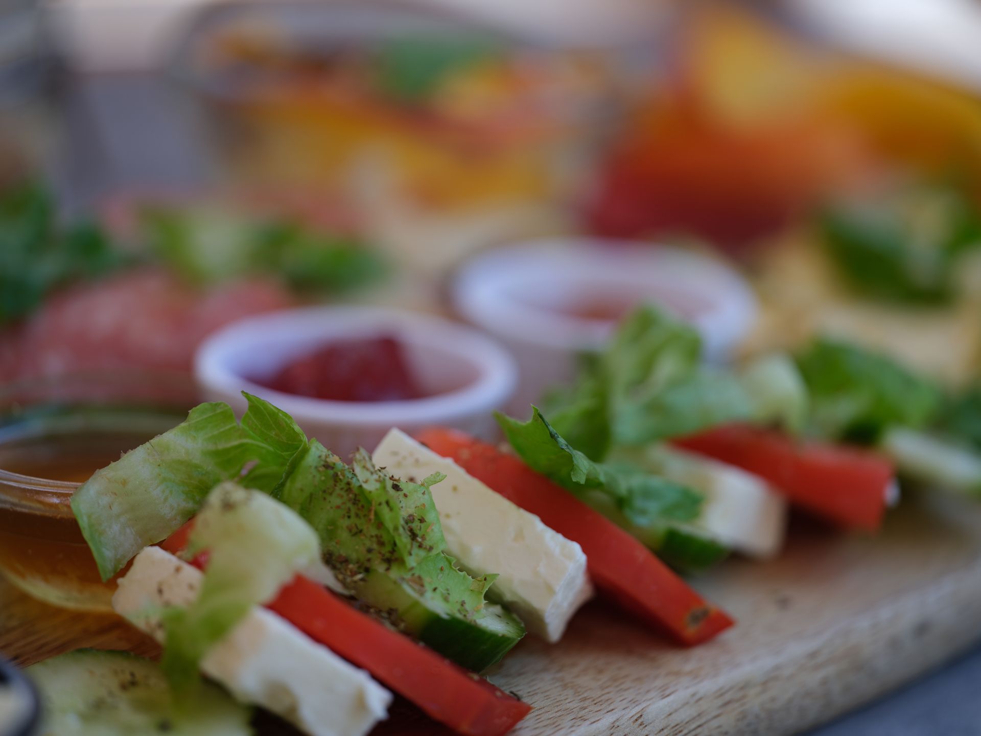 A wooden cutting board topped with sliced vegetables and cheese.