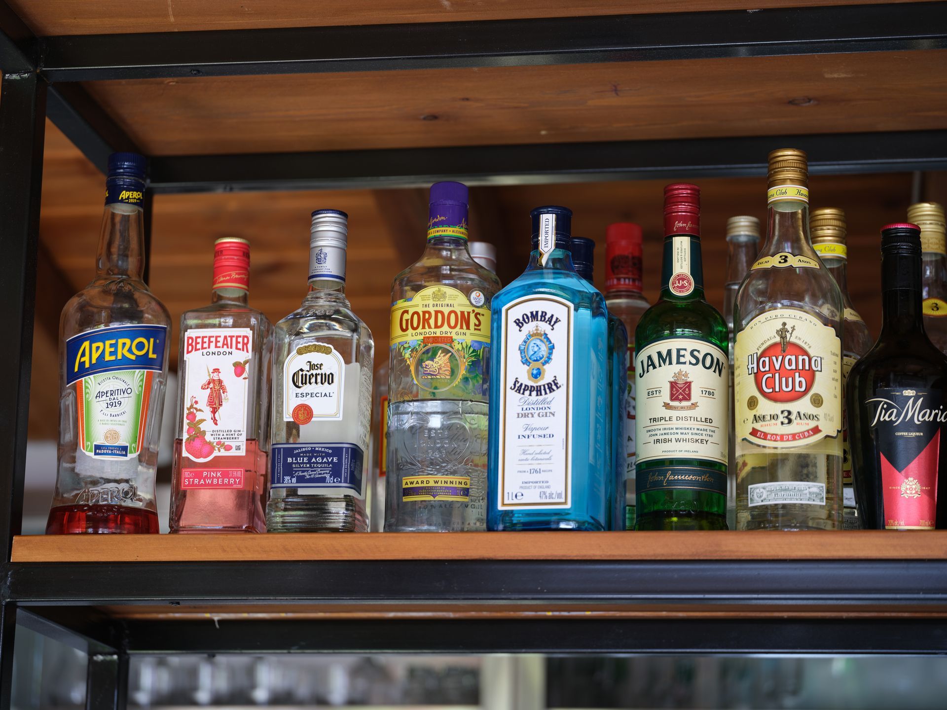 A shelf filled with bottles of alcohol including aperol