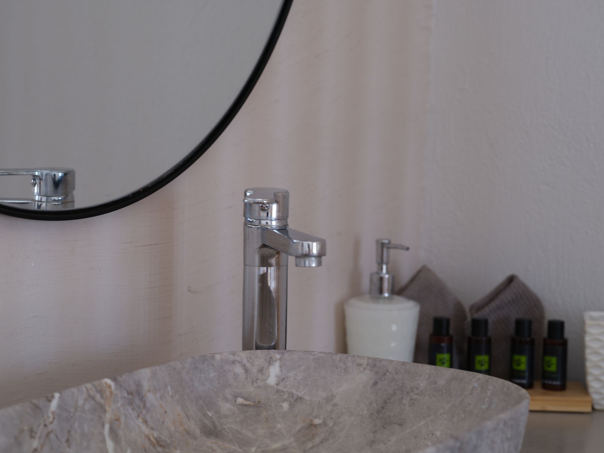 A bathroom sink with a round mirror above it