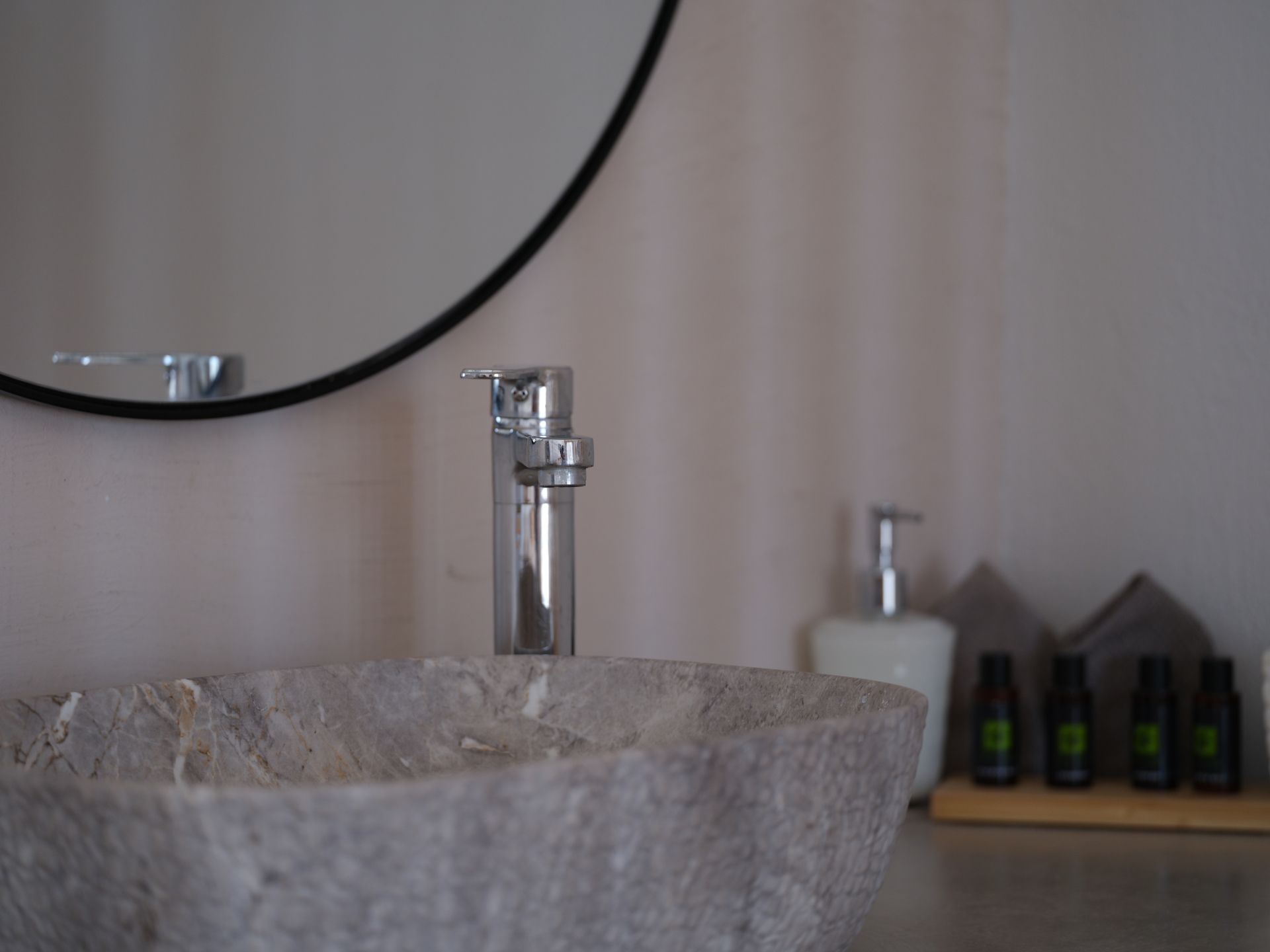 A bathroom sink with a round mirror above it